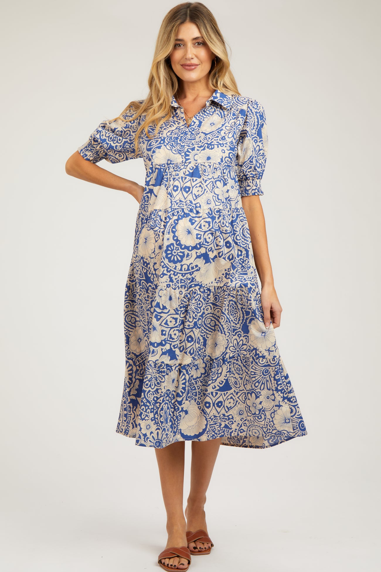 woman wearing a blue and cream patterned maternity dress with short puff sleeves and a flowy skirt, showcasing her baby bump