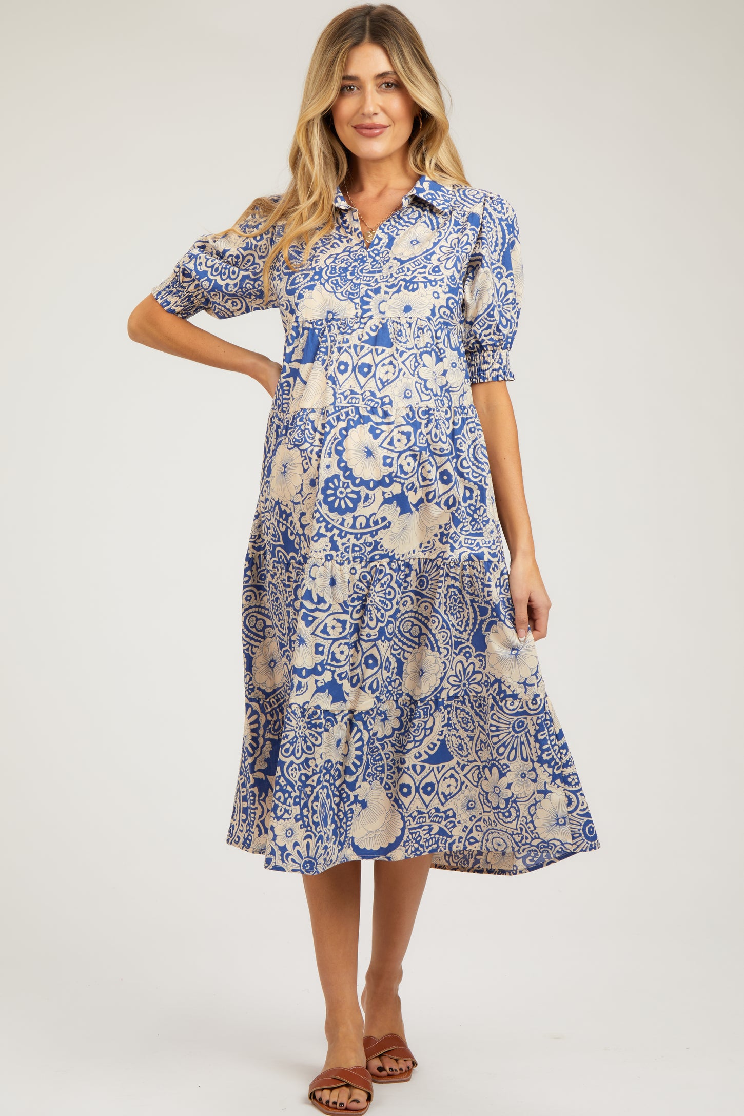 woman wearing a blue and cream patterned maternity dress with short puff sleeves and a flowy skirt, showcasing her baby bump