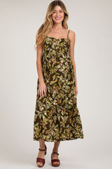 woman wearing a floral print brown maternity maxi dress with adjustable straps and a knot detail at the bust, featuring a baby bump