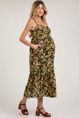 woman wearing a dark floral maternity maxi dress with a baby bump and pockets, standing in strappy brown heels