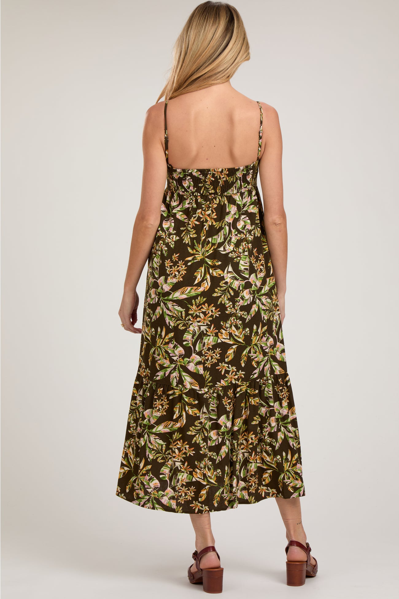 woman wearing a brown floral midi maternity dress with adjustable straps, showing a relaxed fit and tiered design