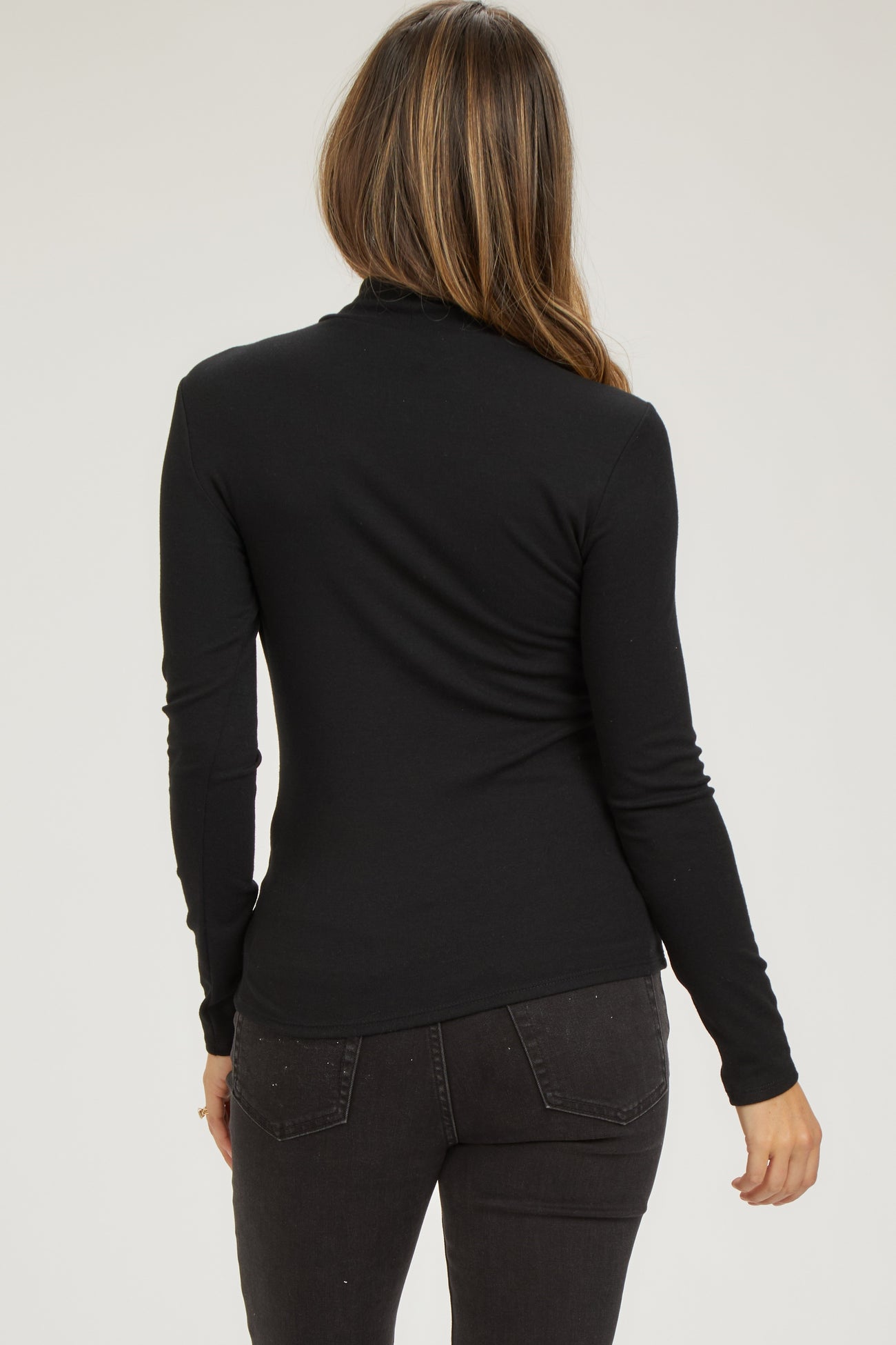 woman wearing a black long sleeve maternity top, showing the back view with a fitted style