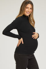 woman wearing a black long sleeve maternity top and showing her baby bump