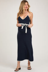 woman wearing a navy blue maternity maxi dress with a white tie belt and a visible baby bump