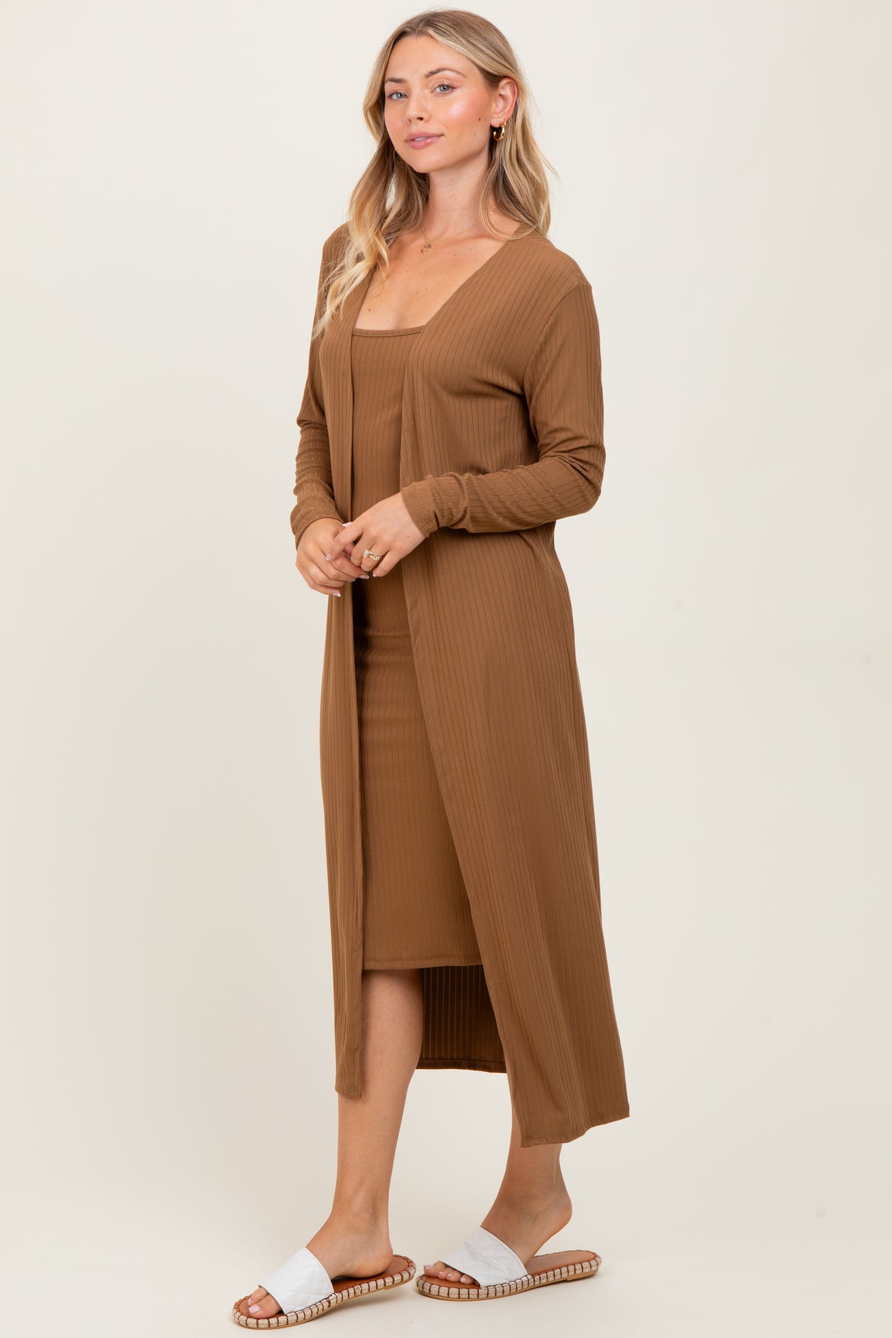 woman wearing a brown ribbed dress and long cardigan, paired with white slide sandals
