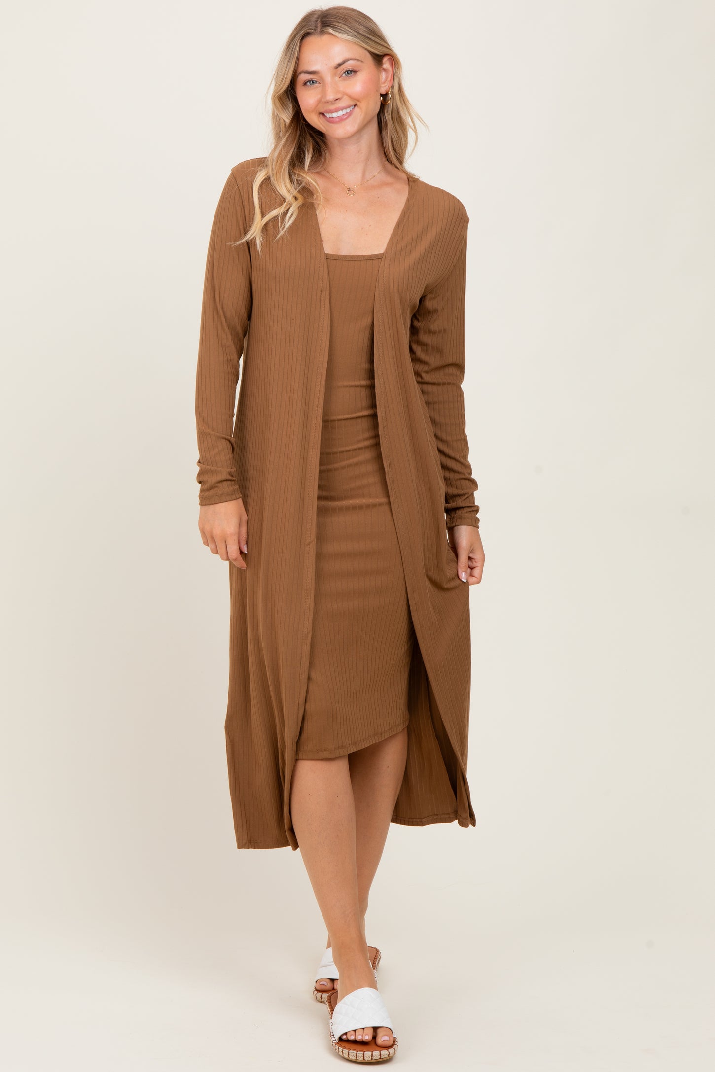 woman wearing a brown ribbed midi dress with a matching long cardigan and white slide sandals