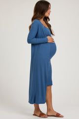 woman wearing a blue ribbed maternity dress with matching long cardigan and holding her baby bump