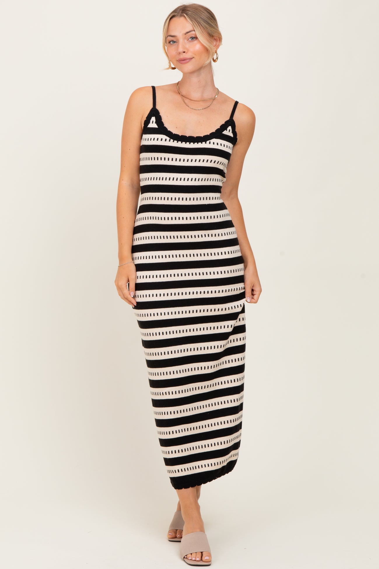 woman wearing a black and cream striped maxi dress with adjustable spaghetti straps and lace trim
