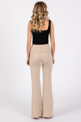 woman wearing a black fitted tank top and light beige flared pants, seen from the back