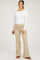 woman wearing a white long sleeve maternity top and beige flared maternity pants, showcasing her baby bump.