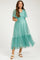 woman wearing a teal maternity dress with a v-neck and tulle tiered skirt, showcasing her baby bump