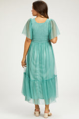woman wearing a mint green maternity maxi dress with short sheer sleeves and a tiered skirt from the back