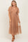woman wearing a tan midi dress with puff sleeves and a tiered tulle skirt, styled with brown sandals