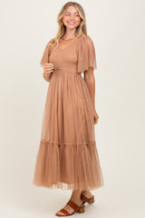 woman wearing a tan tiered maxi dress with puff sleeves and a fitted bodice, styled with brown sandals