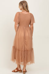 woman wearing a light brown tulle maxi dress with short puff sleeves and a tiered skirt, viewed from the back