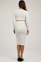 woman wearing a white ribbed maternity crop top and fitted midi skirt, showing her baby bump from the back