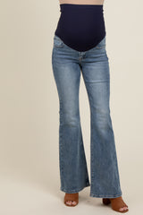 woman wearing blue maternity flared jeans with a high waistband, showcasing a baby bump