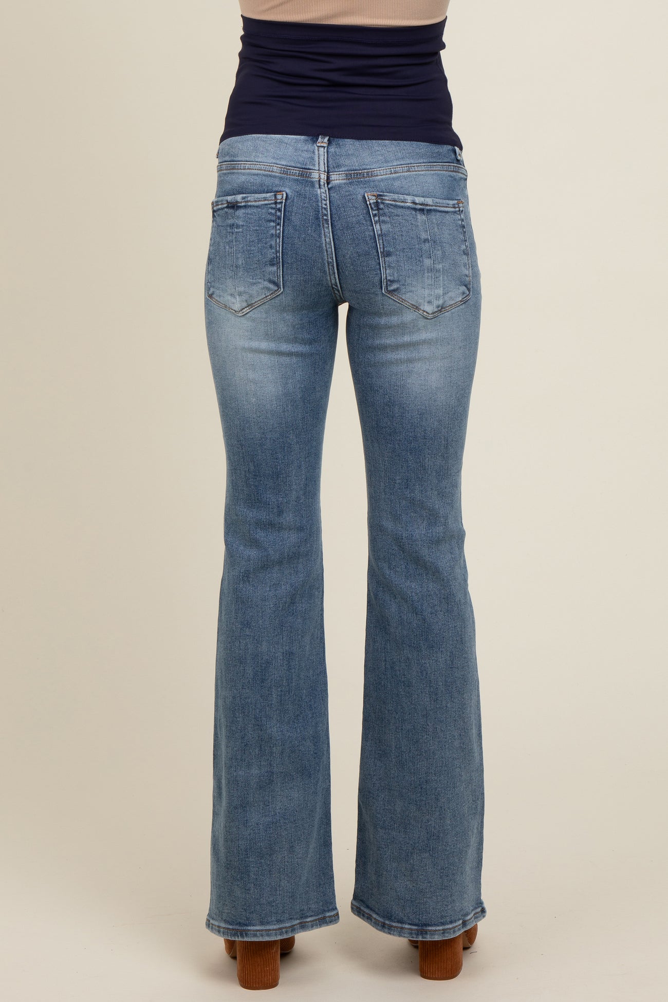 woman wearing light blue maternity flared jeans, viewed from the back, showcasing the fitted waist and pockets