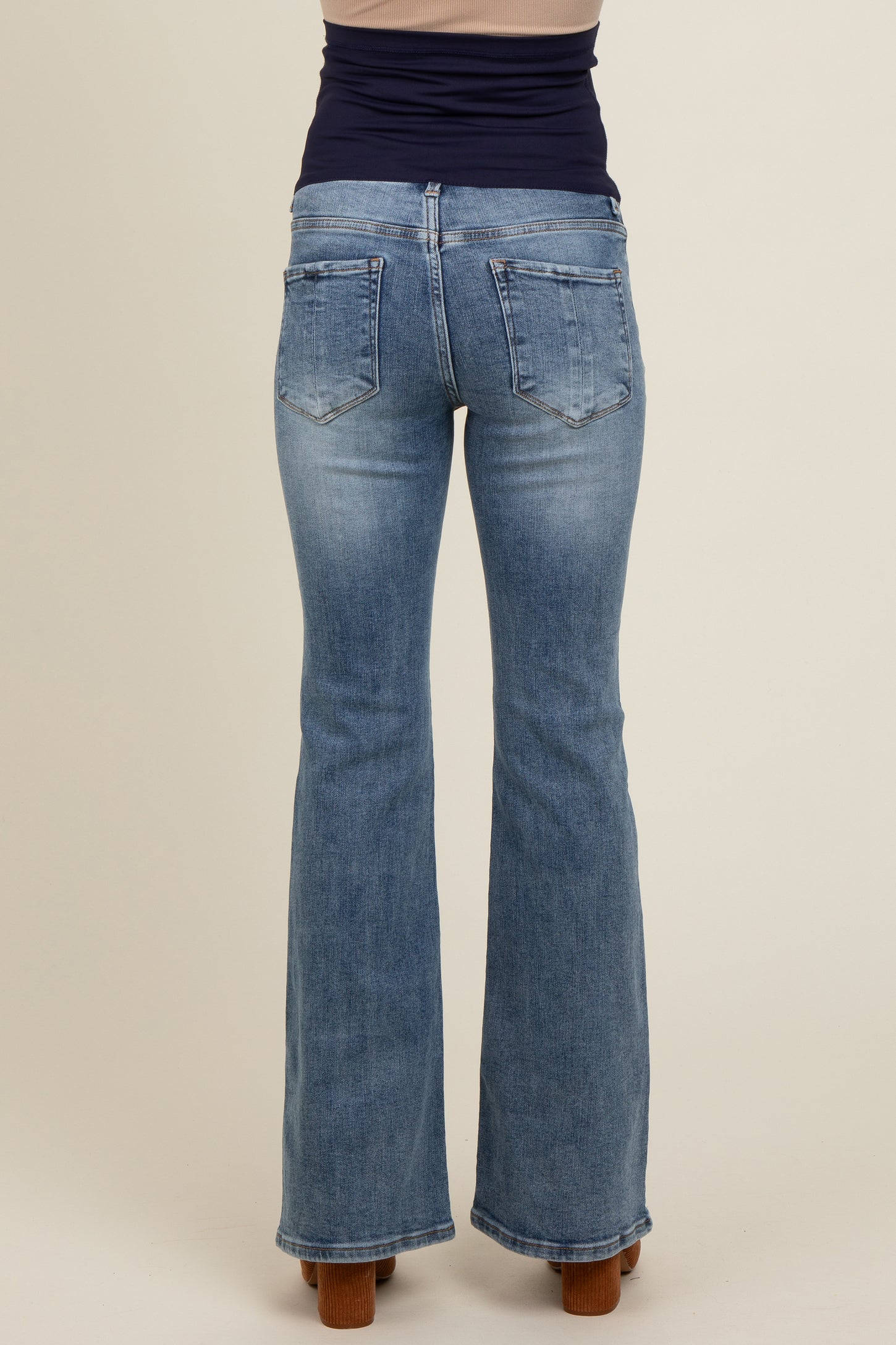 woman wearing light blue maternity flared jeans, viewed from the back, showcasing the fitted waist and pockets