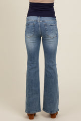 woman wearing light blue maternity flared jeans, viewed from the back, showcasing the fitted waist and pockets