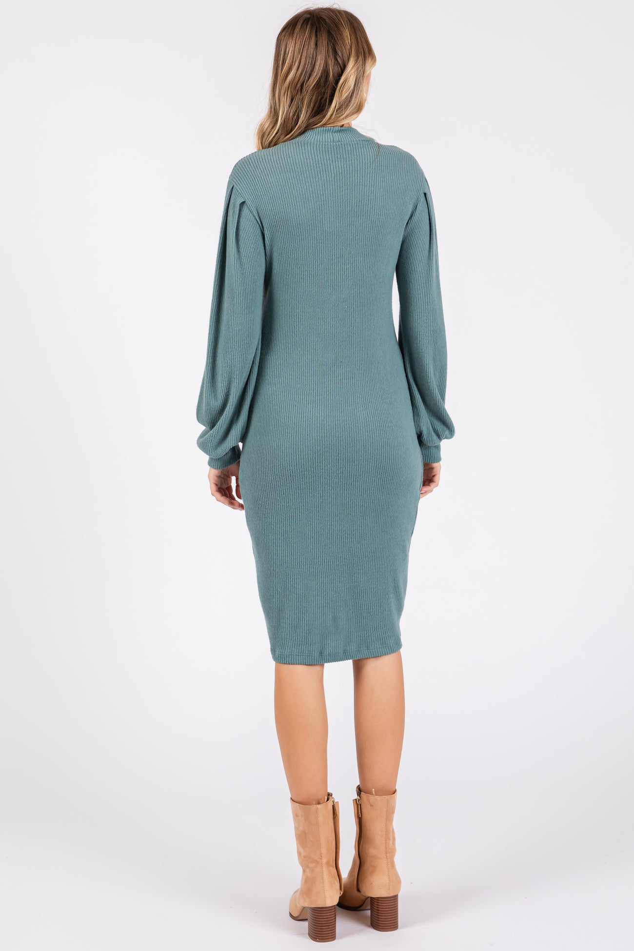 woman wearing a teal ribbed long sleeve midi dress and tan ankle boots, viewed from the back