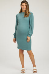 woman wearing a teal ribbed maternity dress with puff sleeves and showing her baby bump