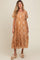 woman wearing a tan floral patterned maternity dress with puff sleeves and a tiered skirt