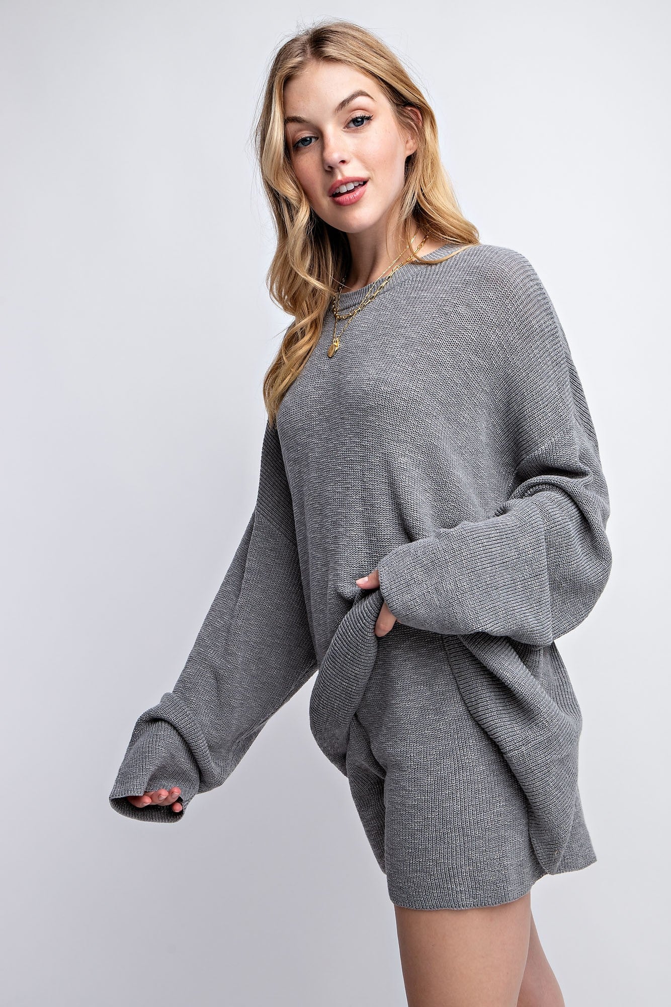 woman wearing a grey oversized ribbed sweater with bell sleeves and matching shorts, styled casually