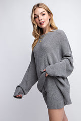 woman wearing a grey oversized ribbed sweater with bell sleeves and matching shorts, styled casually