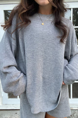 woman wearing an oversized gray knit sweater with long sleeves and a relaxed fit, hands in pockets