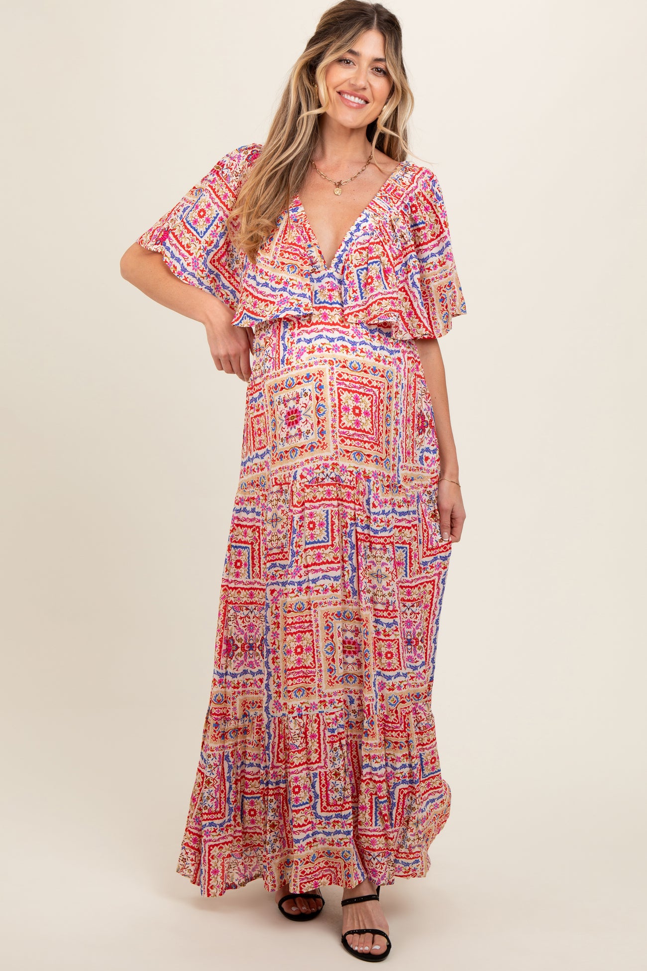 woman wearing a colorful patterned maternity maxi dress with flutter sleeves and a v-neckline, showcasing a baby bump