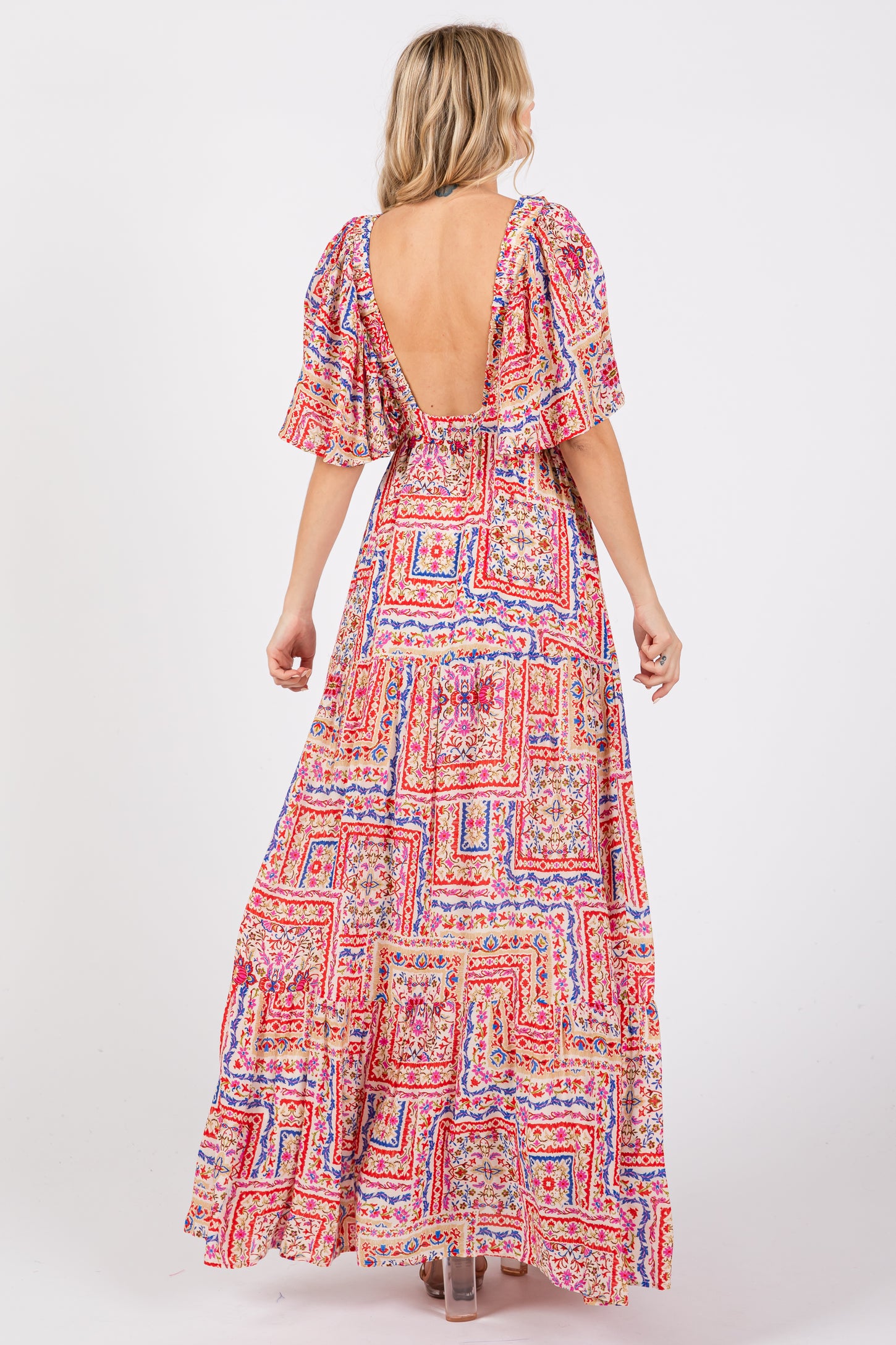 woman wearing a colorful patterned maxi dress with a deep V-back and short puff sleeves