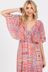 woman wearing a colorful floral patterned maxi dress with flutter sleeves and a deep V-neckline