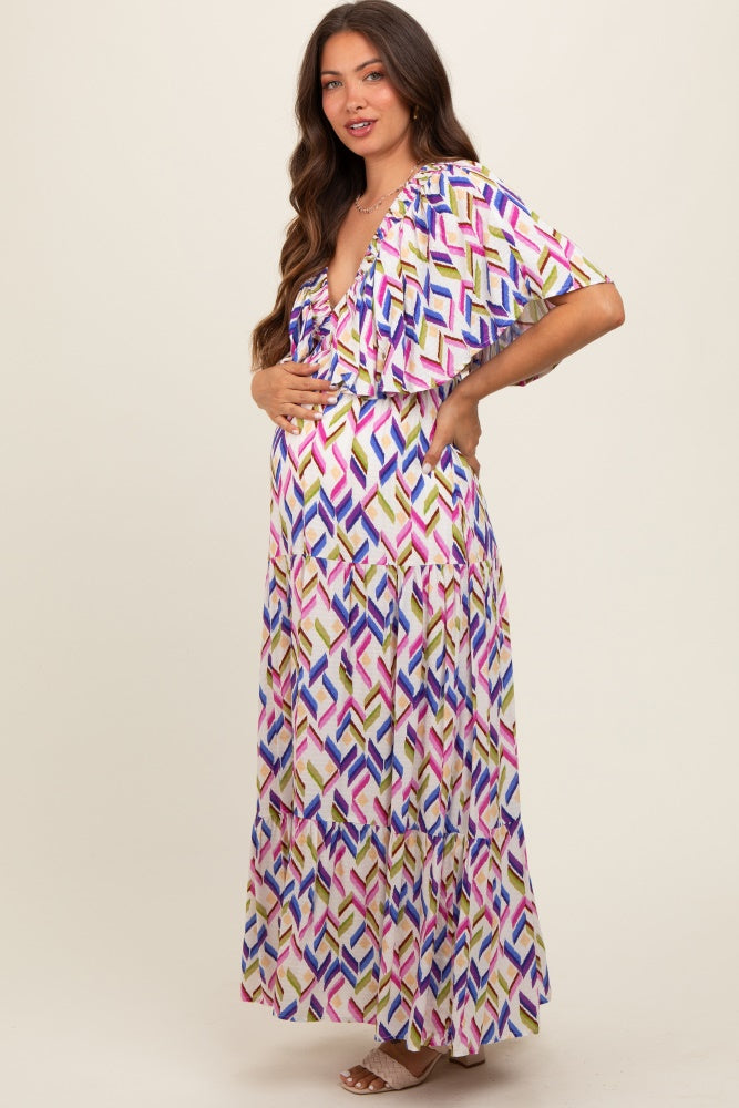 woman wearing a colorful patterned maternity maxi dress and posing with her baby bump