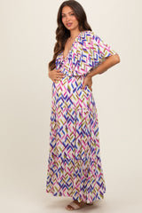 woman wearing a colorful patterned maternity maxi dress and posing with her baby bump
