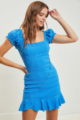 woman wearing a bright blue short sleeve fitted dress with ruffled sleeves and a flared hem