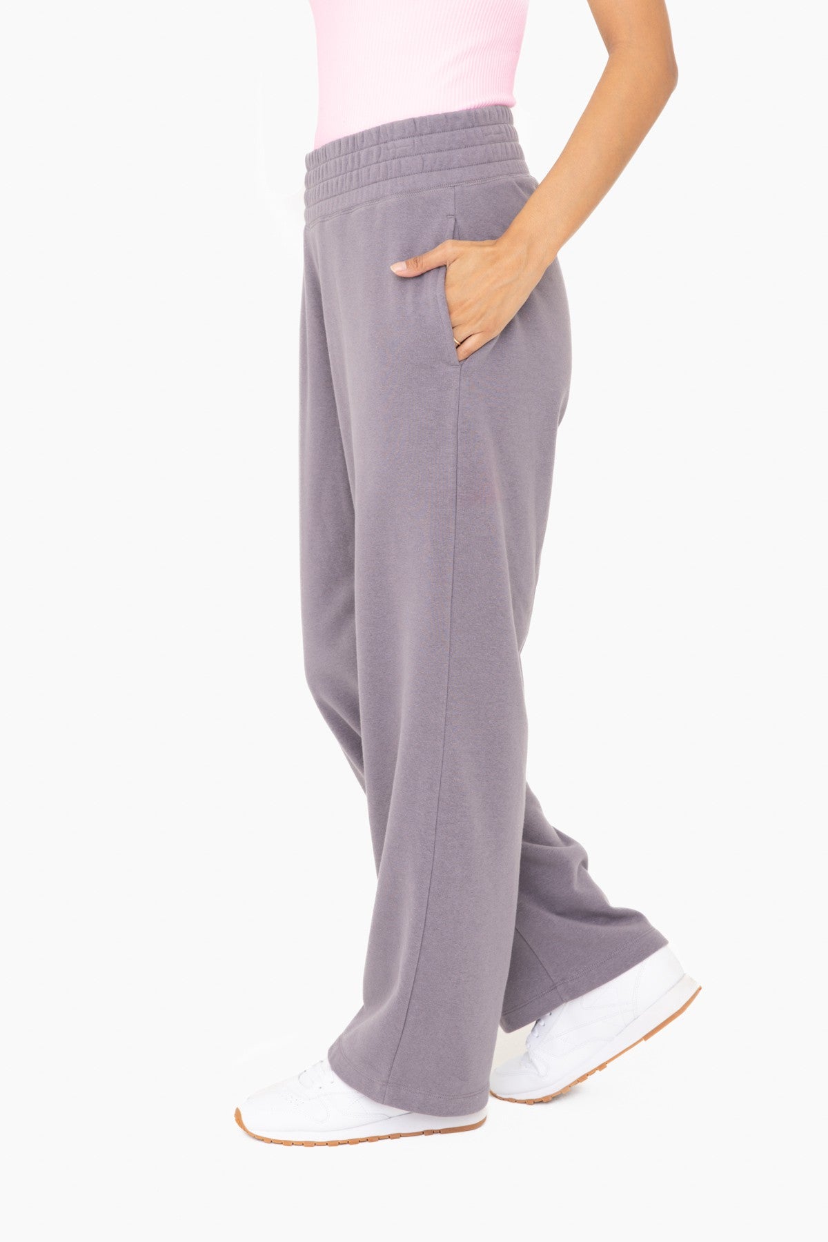 woman wearing high-waisted purple wide-leg sweatpants with pockets and white sneakers