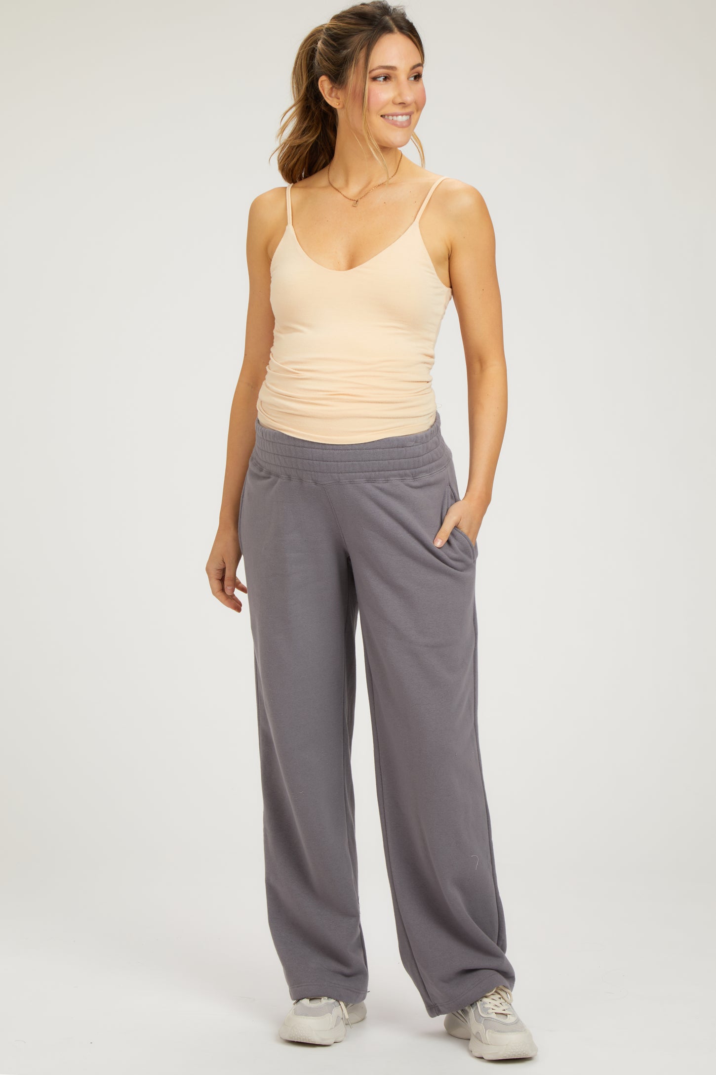 woman wearing a beige maternity tank top and gray maternity lounge pants with pockets