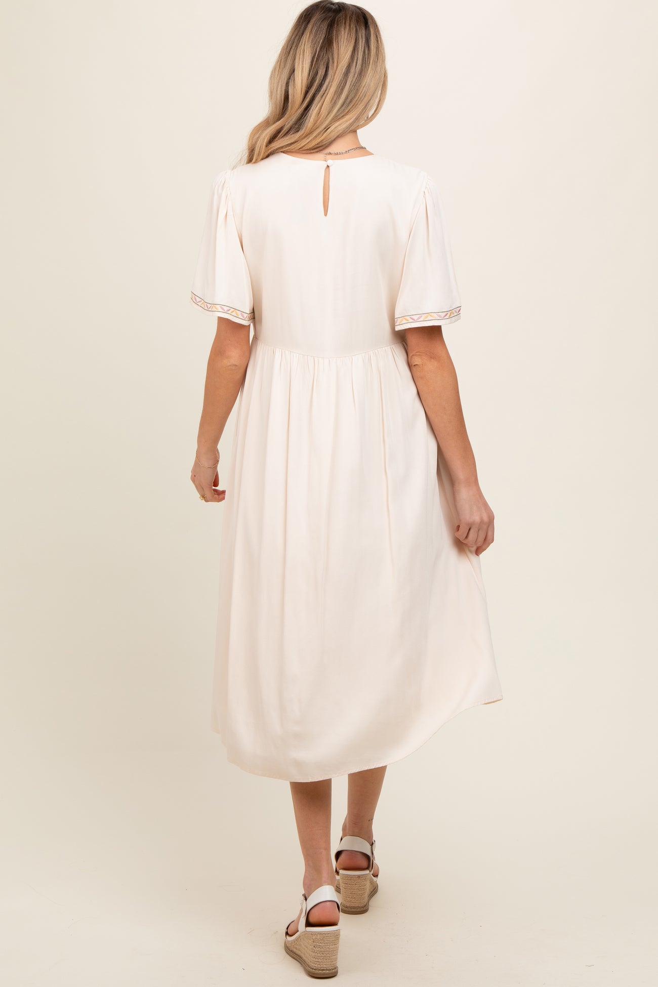 woman wearing a light pink maternity dress with short sleeves and a back keyhole detail