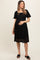woman wearing a black lace maternity dress, smiling and holding her baby bump