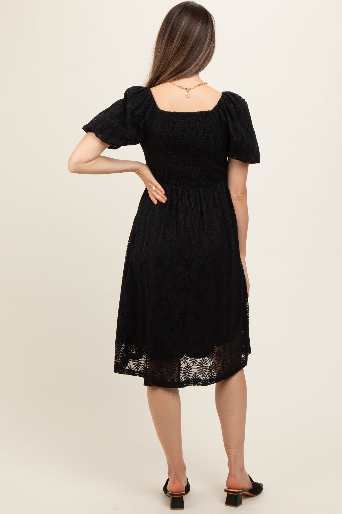 woman wearing a black maternity dress with puff sleeves and a fitted bodice, showing a relaxed fit at the back