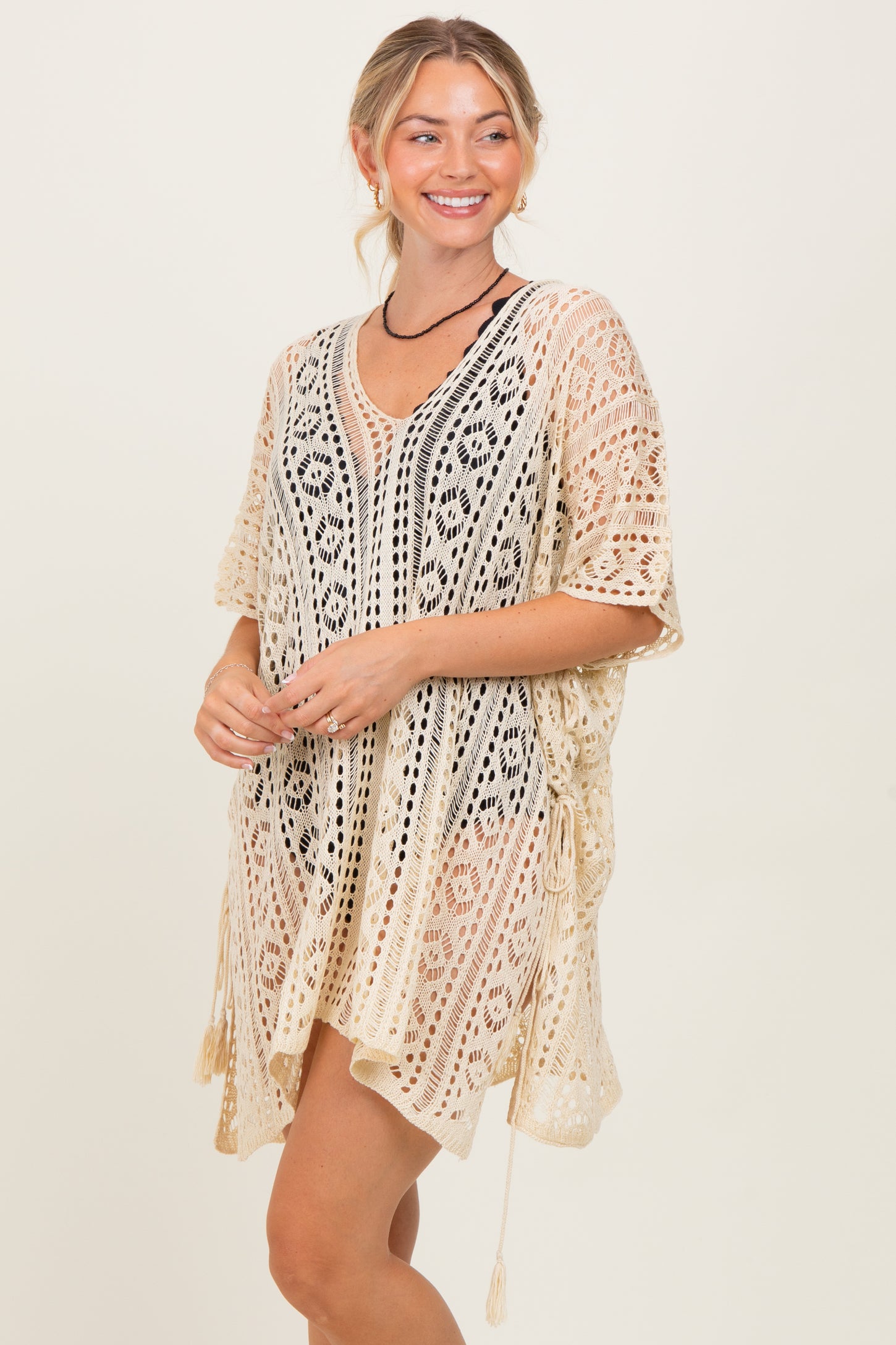 woman wearing a beige crochet cover-up with a v-neck and side ties