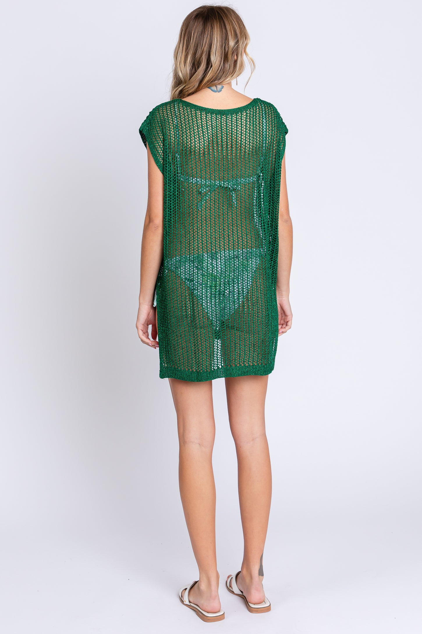 woman wearing a green open-knit cover-up with short sleeves, shown from the back