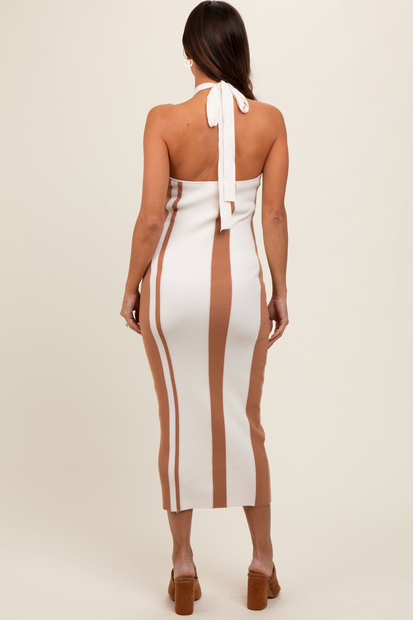 woman wearing a striped beige and white maternity dress with a halter neck and back tie detail
