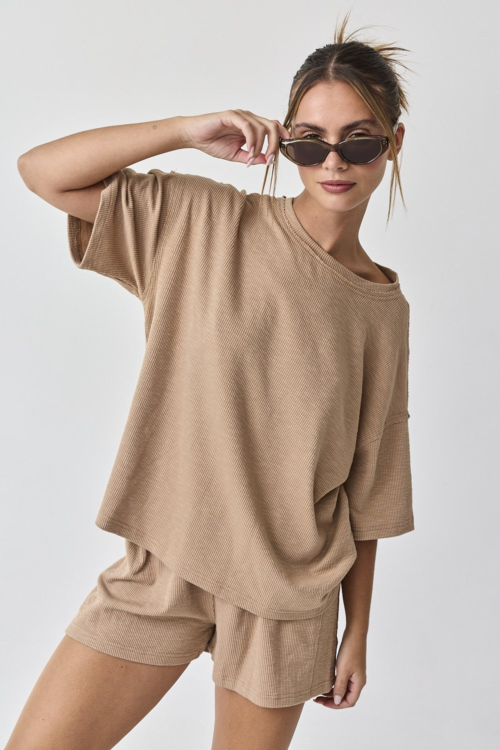 woman wearing a beige oversized short sleeve top and matching shorts, styled with sunglasses