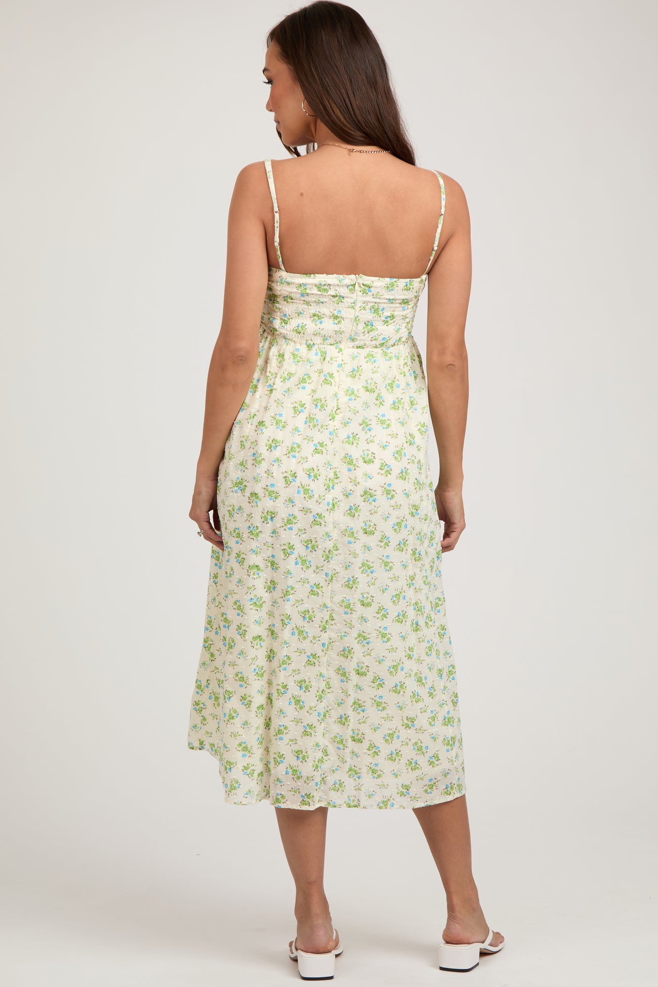 woman wearing a floral green and white maternity dress with adjustable straps and a flowing silhouette