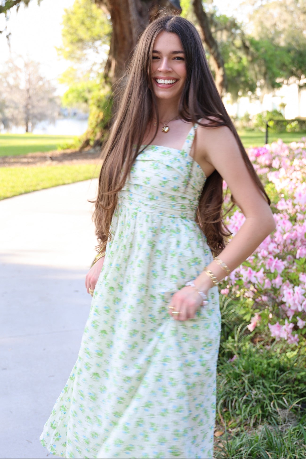 woman wearing a light green floral maxi dress with spaghetti straps and smiling outdoors