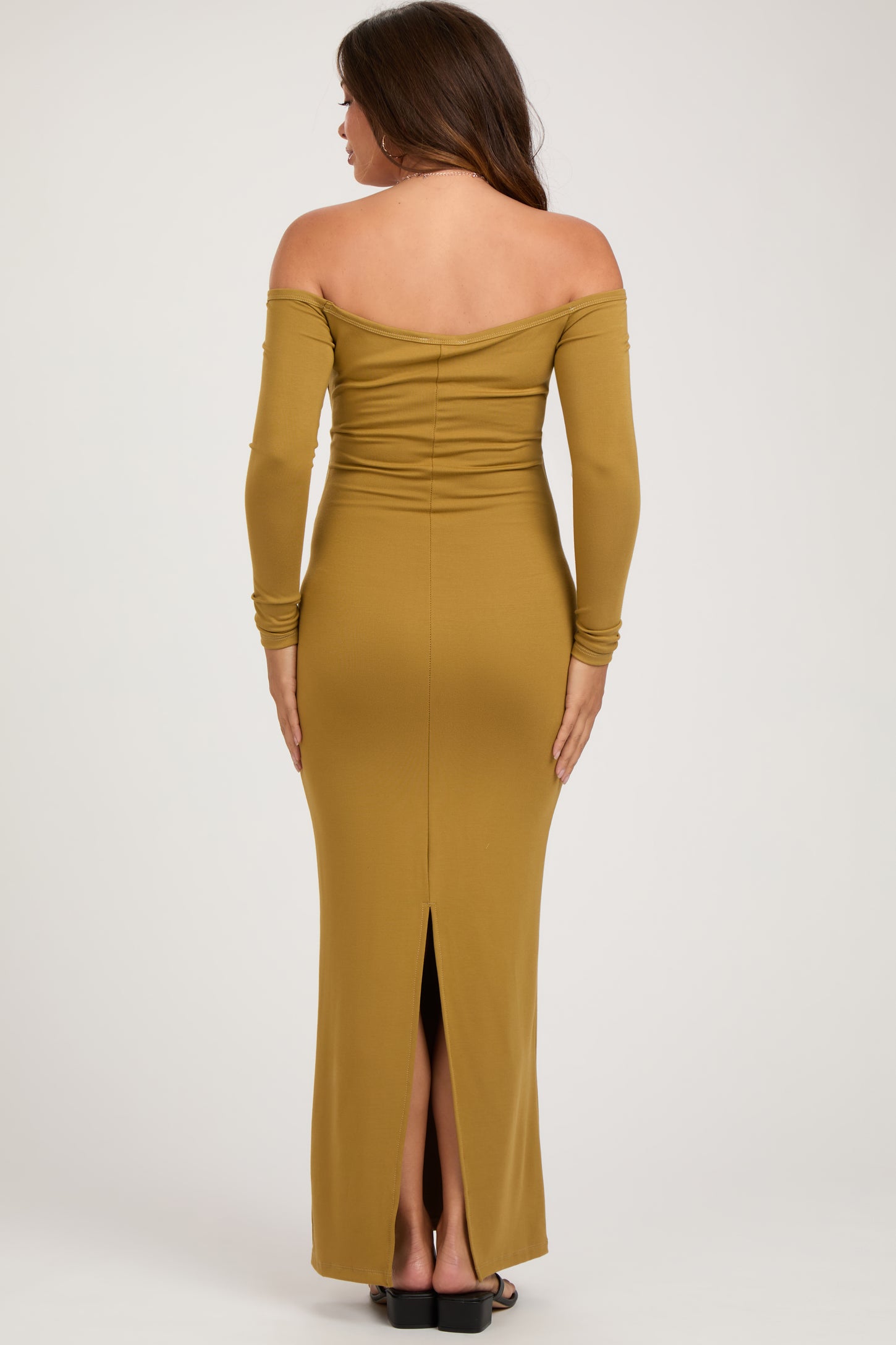 woman wearing a mustard off-shoulder maternity dress with a fitted silhouette and a thigh-high slit at the back