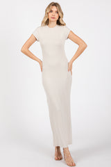 woman wearing a beige short sleeve maxi dress with a fitted silhouette and side slits