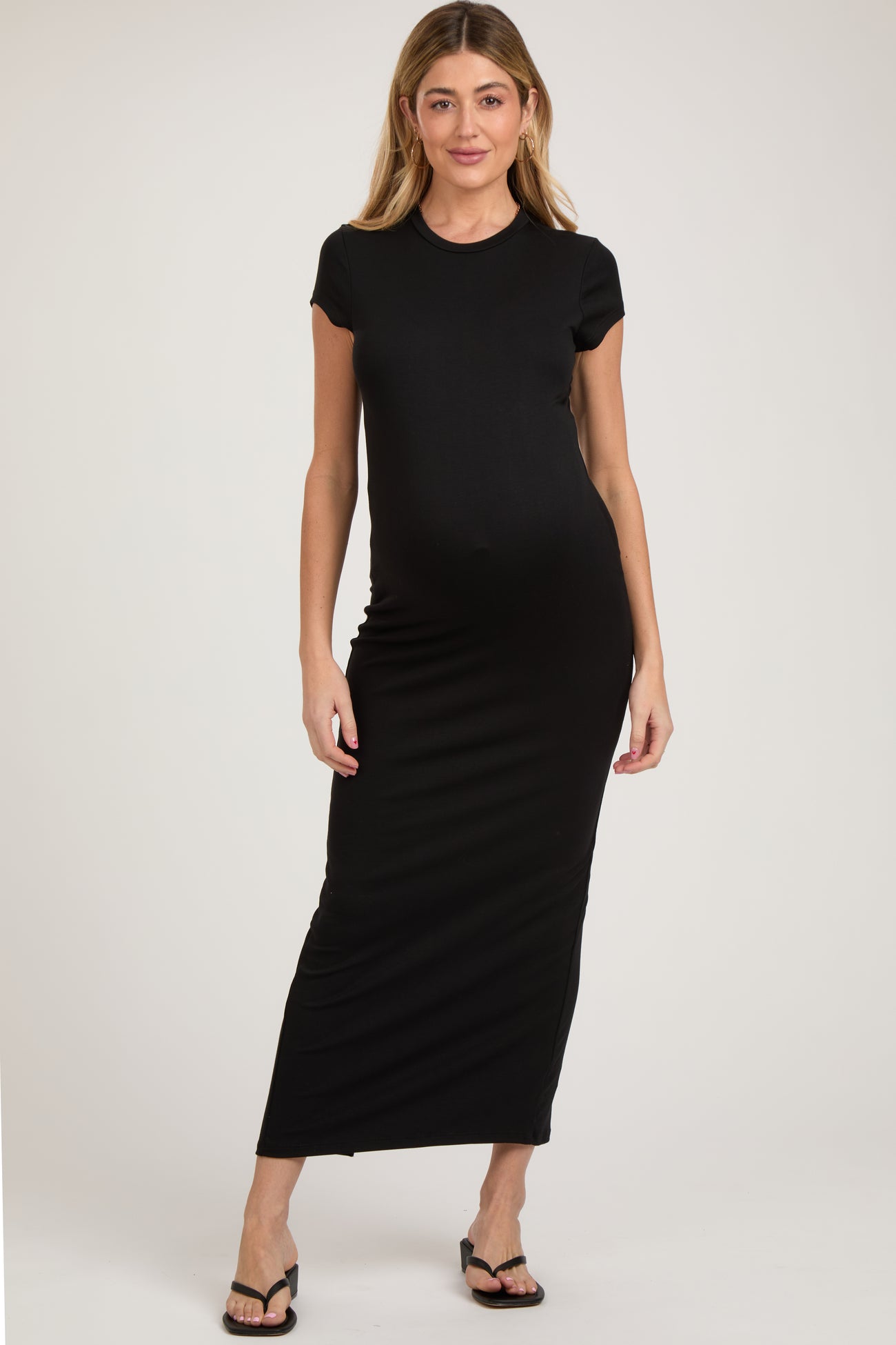 woman wearing a black cap sleeve maternity maxi dress and showcasing her baby bump